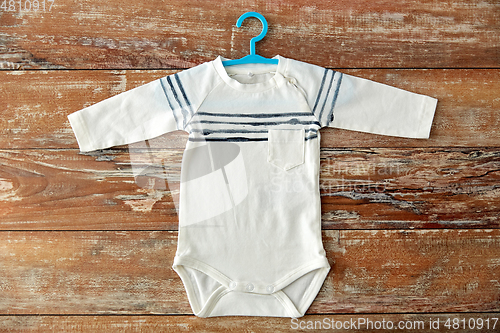 Image of baby bodysuit with hanger on wooden table