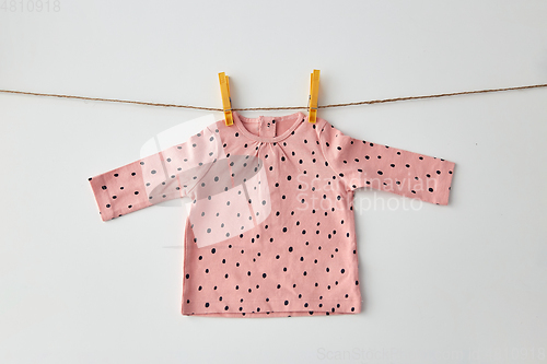 Image of pink shirt for baby girl hanging on rope with pins