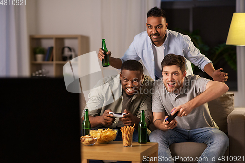 Image of happy friends playing video games at home at night