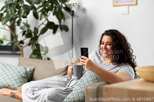 Image of woman with smartphone drinking coffee at home