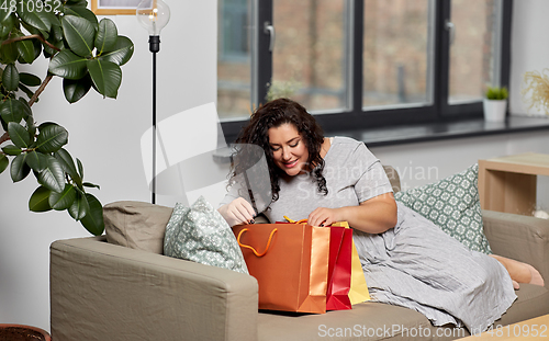 Image of happy young woman with shopping bags at home