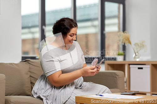 Image of woman with money, papers and calculator at home