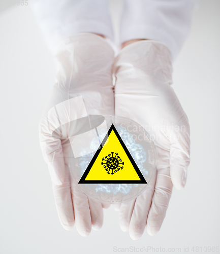 Image of hands with coronavirus test and caution sign