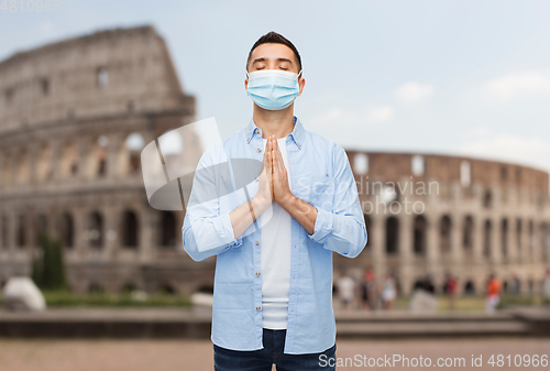 Image of praying man wearing medical mask in italy