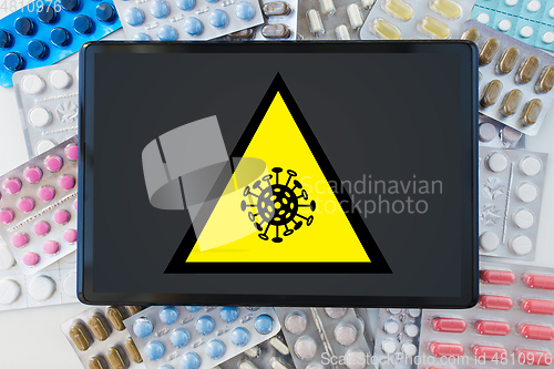 Image of coronavirus caution sign, tablet pc and drugs