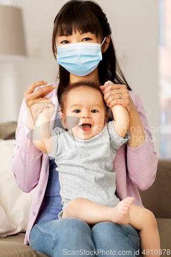 Image of asian mother in protective mask with baby at home