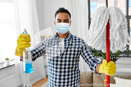 Image of asian woman in protective mask cleaning home