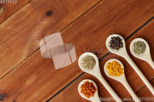 Image of spoons with different spices on wooden table