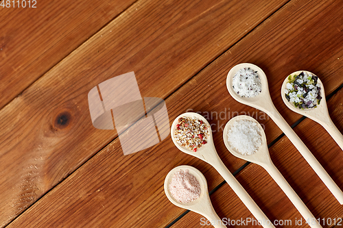 Image of spoons with salt and spices on wooden table