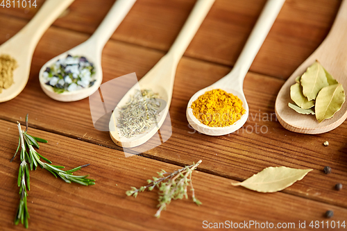 Image of spoons with spices and salt on wooden table