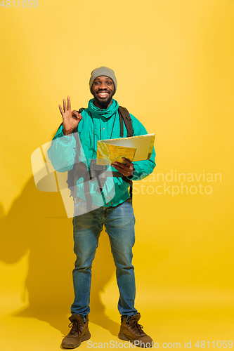 Image of Full length portrait of a cheerful young african tourist guy isolated on yellow background