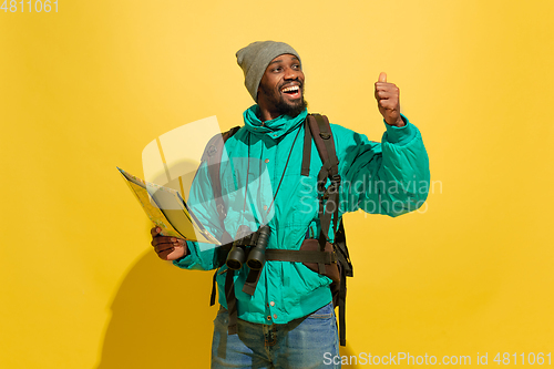 Image of Full length portrait of a cheerful young african tourist guy isolated on yellow background