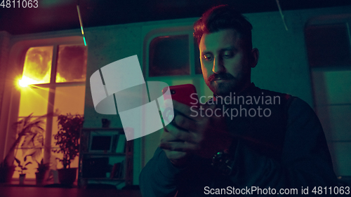 Image of Cinematic portrait of handsome man in neon lighted interior