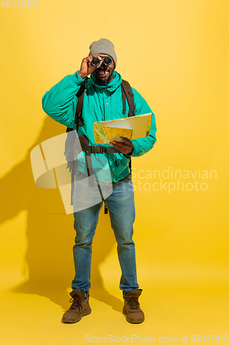 Image of Full length portrait of a cheerful young african tourist guy isolated on yellow background