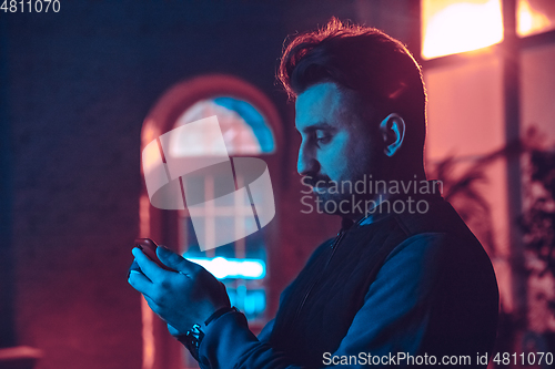 Image of Cinematic portrait of handsome man in neon lighted interior