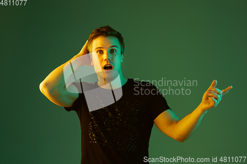 Image of Caucasian man\'s portrait isolated on green studio background in neon light