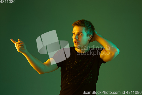 Image of Caucasian man\'s portrait isolated on green studio background in neon light