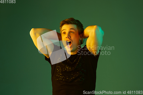 Image of Caucasian man\'s portrait isolated on green studio background in neon light