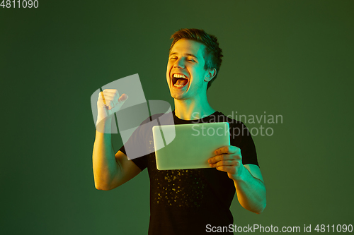 Image of Caucasian man\'s portrait isolated on green studio background in neon light