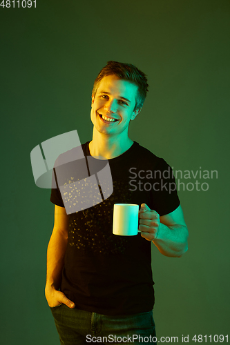 Image of Caucasian man\'s portrait isolated on green studio background in neon light