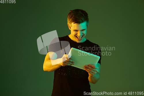 Image of Caucasian man\'s portrait isolated on green studio background in neon light