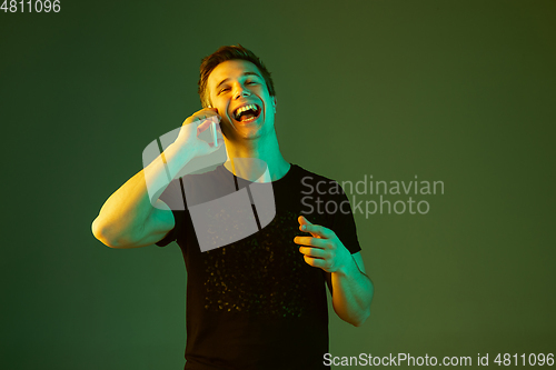 Image of Caucasian man\'s portrait isolated on green studio background in neon light