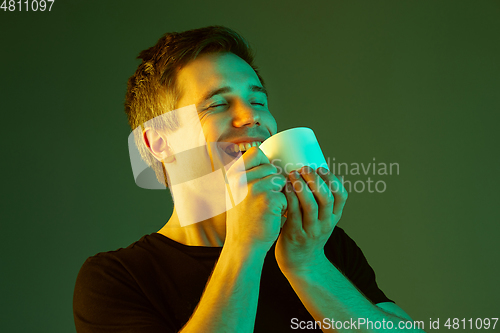 Image of Caucasian man\'s portrait isolated on green studio background in neon light