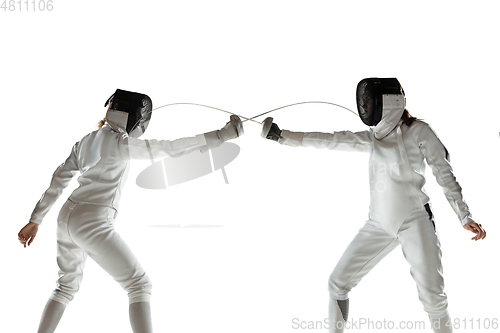 Image of Teen girls in fencing costumes with swords in hands isolated on white background