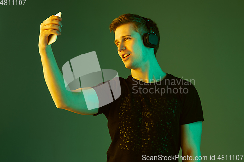 Image of Caucasian man\'s portrait isolated on green studio background in neon light