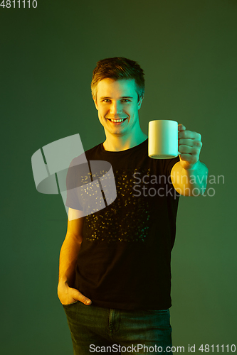 Image of Caucasian man\'s portrait isolated on green studio background in neon light