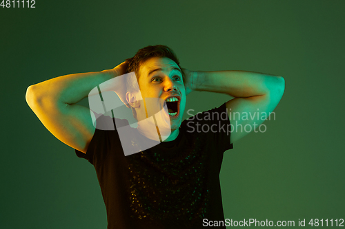 Image of Caucasian man\'s portrait isolated on green studio background in neon light