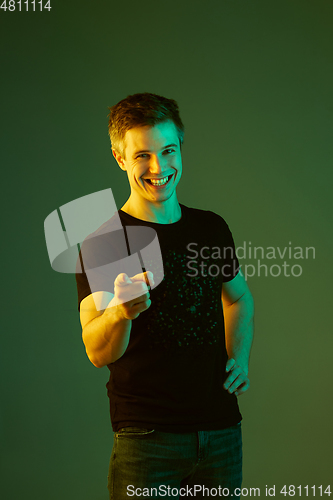 Image of Caucasian man\'s portrait isolated on green studio background in neon light
