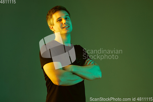 Image of Caucasian man\'s portrait isolated on green studio background in neon light