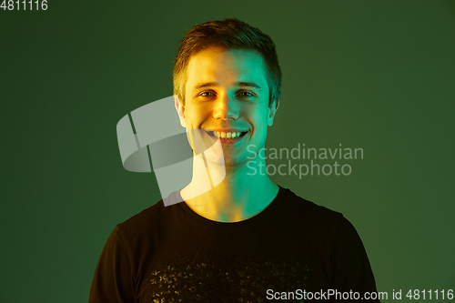 Image of Caucasian man\'s portrait isolated on green studio background in neon light