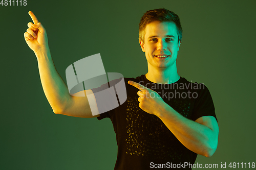Image of Caucasian man\'s portrait isolated on green studio background in neon light
