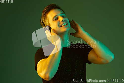 Image of Caucasian man\'s portrait isolated on green studio background in neon light