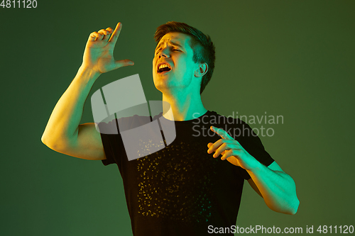 Image of Caucasian man\'s portrait isolated on green studio background in neon light