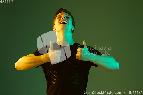 Image of Caucasian man\'s portrait isolated on green studio background in neon light