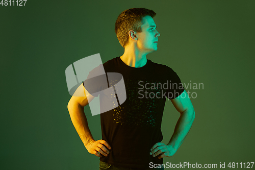 Image of Caucasian man\'s portrait isolated on green studio background in neon light