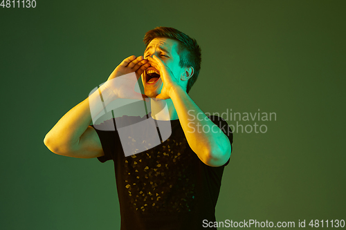Image of Caucasian man\'s portrait isolated on green studio background in neon light