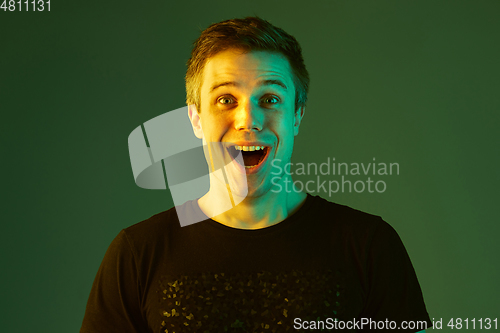 Image of Caucasian man\'s portrait isolated on green studio background in neon light