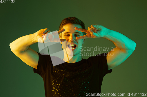 Image of Caucasian man\'s portrait isolated on green studio background in neon light