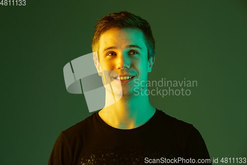 Image of Caucasian man\'s portrait isolated on green studio background in neon light