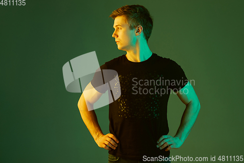 Image of Caucasian man\'s portrait isolated on green studio background in neon light