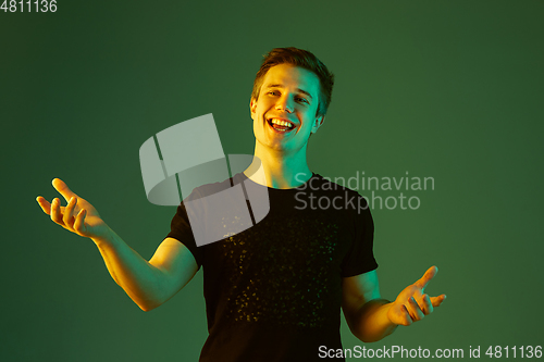 Image of Caucasian man\'s portrait isolated on green studio background in neon light