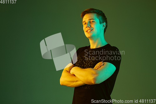 Image of Caucasian man\'s portrait isolated on green studio background in neon light