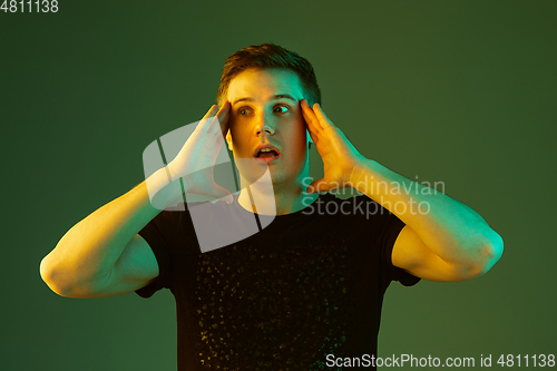 Image of Caucasian man\'s portrait isolated on green studio background in neon light
