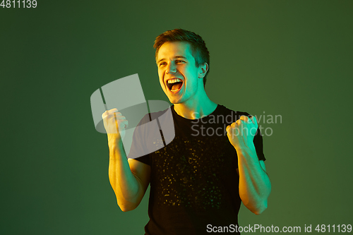 Image of Caucasian man\'s portrait isolated on green studio background in neon light