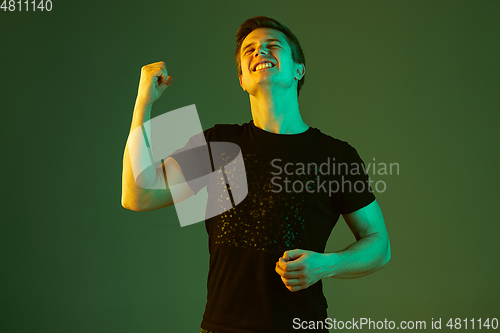 Image of Caucasian man\'s portrait isolated on green studio background in neon light