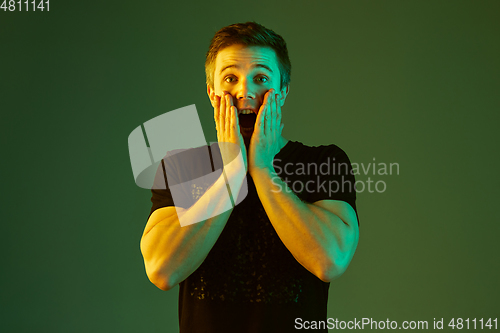 Image of Caucasian man\'s portrait isolated on green studio background in neon light